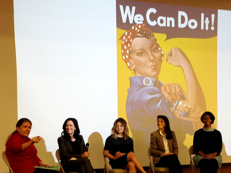 Women sit on stage at ADVANCE seminar.